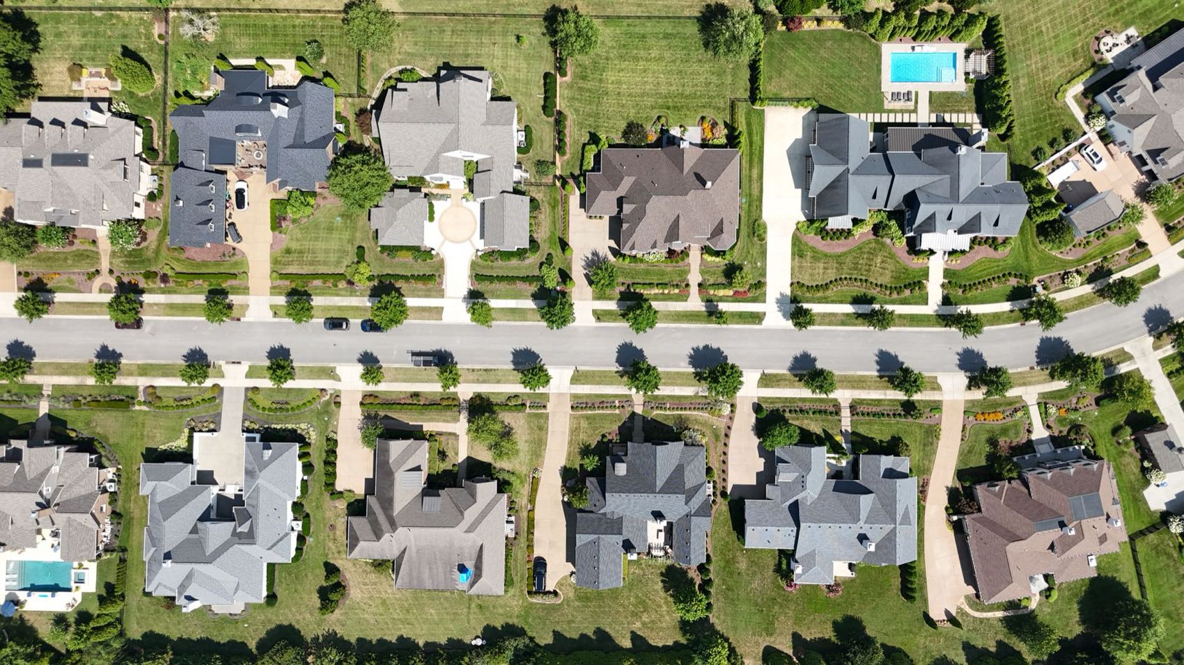 Aerial view of a suburban neighborhood in summer with tree-lined streets