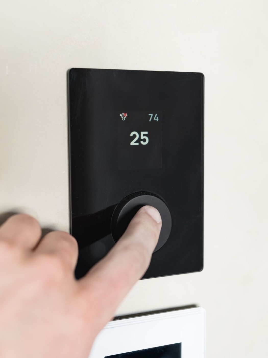 Homeowner programming a modern wall-mounted thermostat